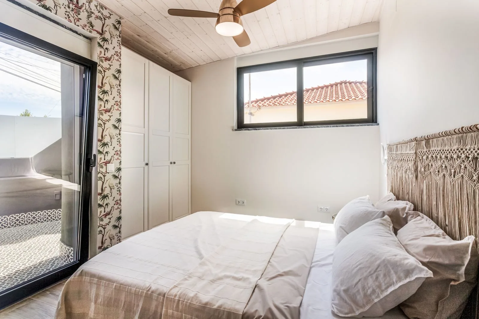 Guest bedroom with botanical wallpaper and macramé headboard — Amoreira loft Cascais by Maya's Homes