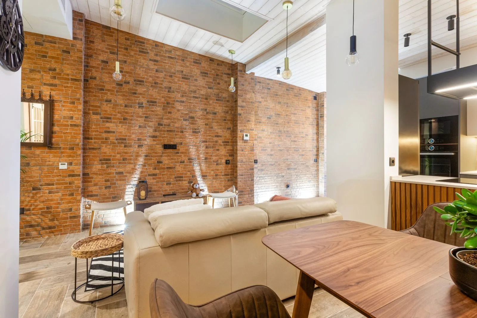 Exposed brick feature wall in open-plan living room — loft conversion Amoreira Cascais by Maya's Homes