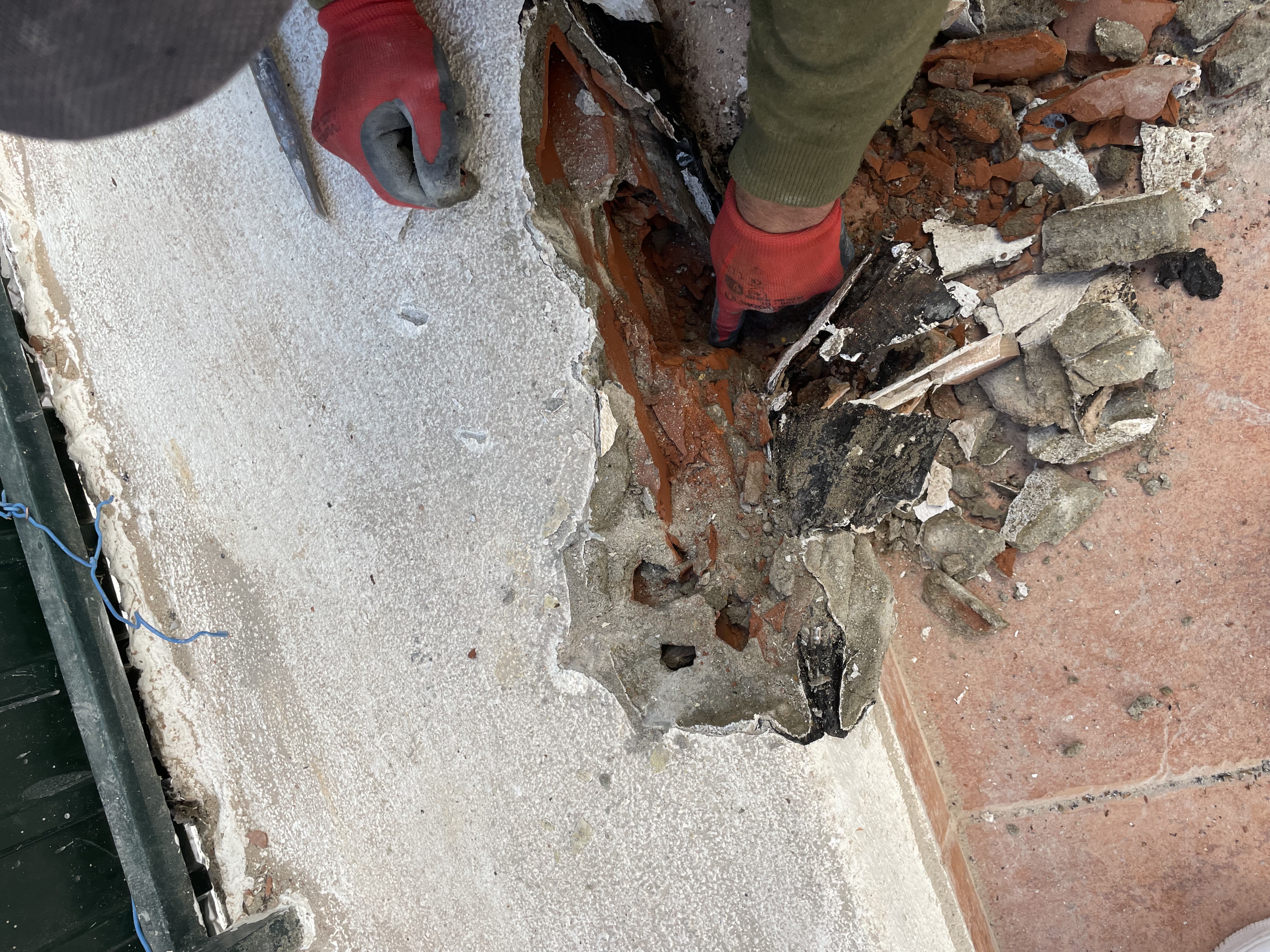 Rosa during &mdash; pulling back a section of the old patio floor reveals rotten material underneath, no waterproofing membrane between the tile and the building structure, decades of leak damage exposed