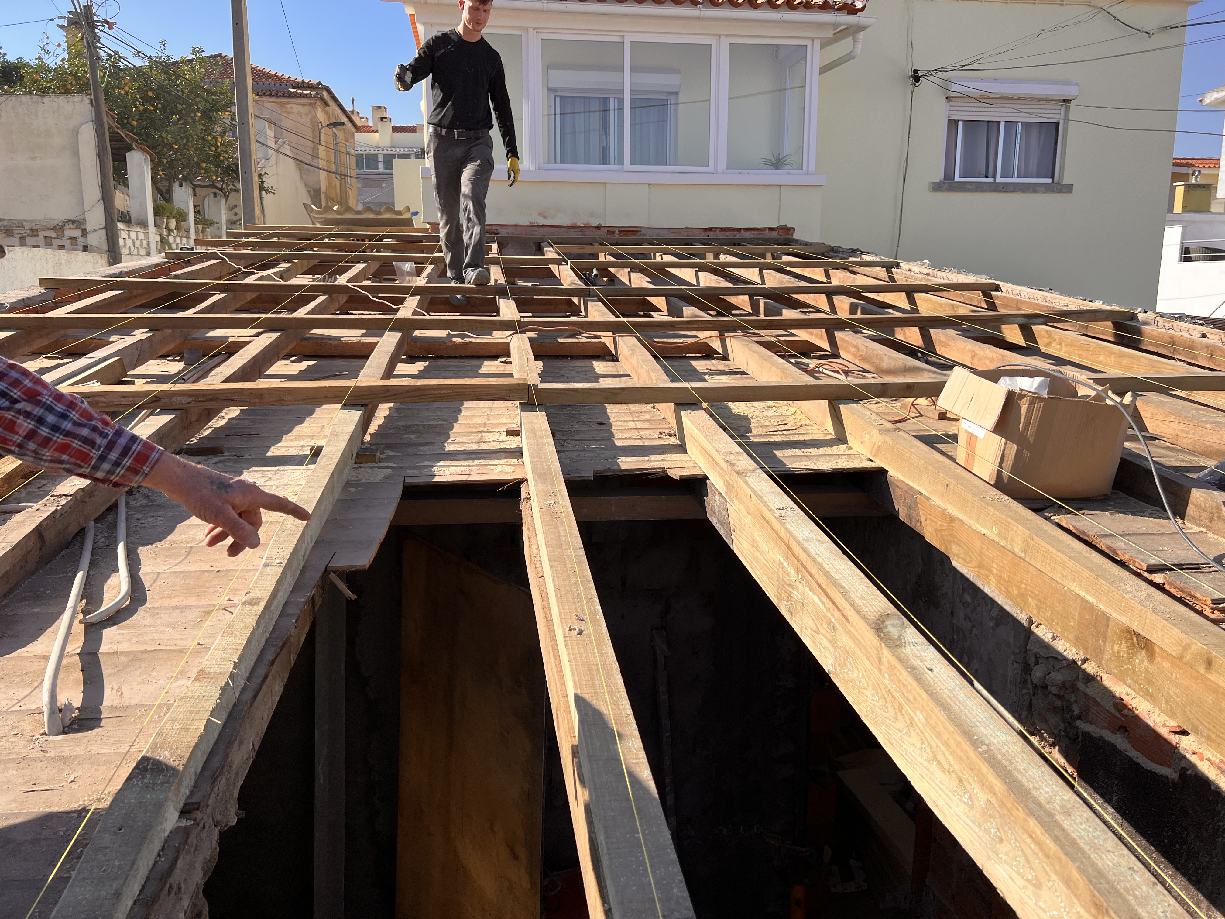The Tasca during &mdash; the roof tiles removed, the timber joist skeleton fully exposed, a worker walking on the joists overhead