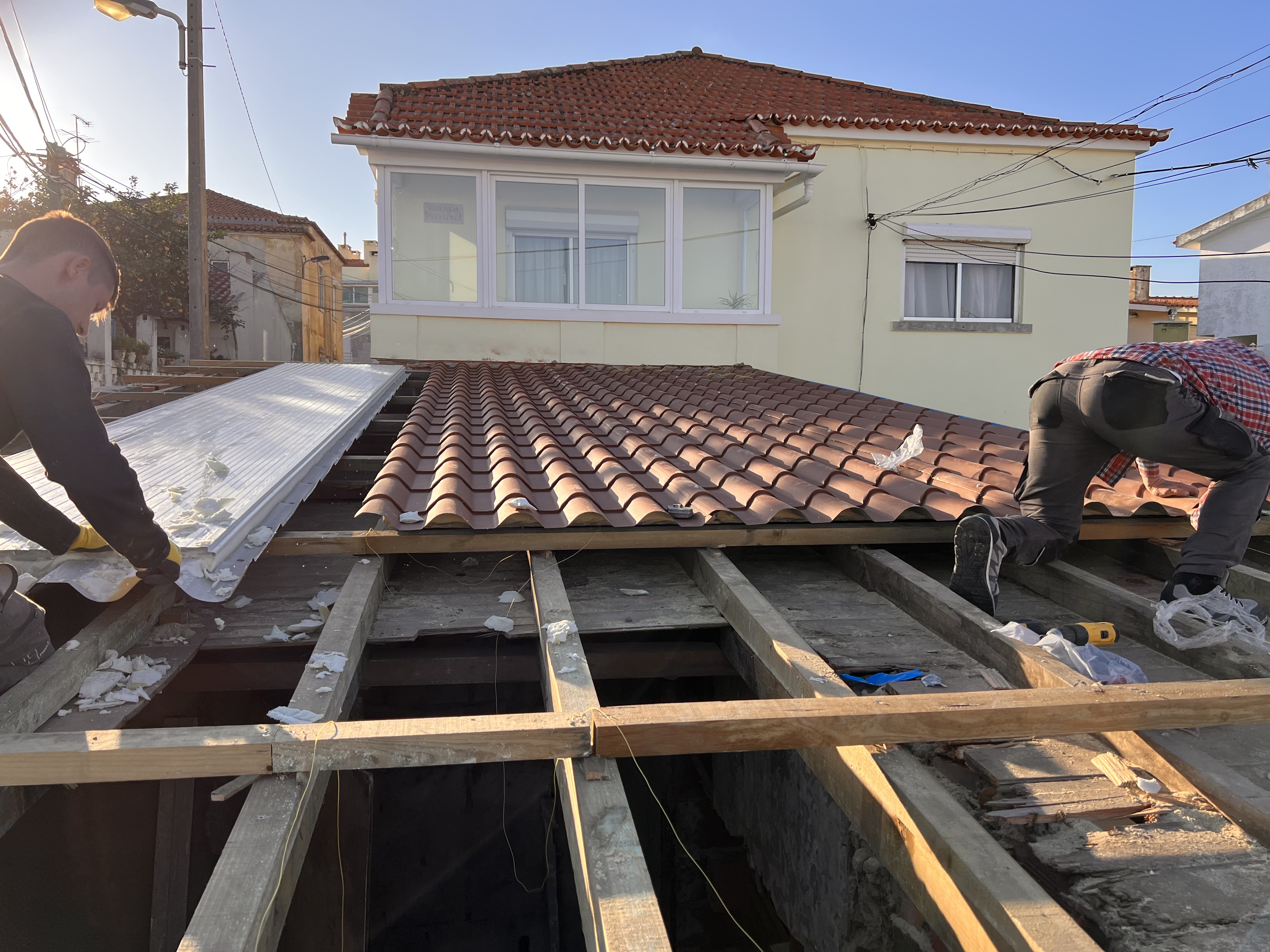The Tasca during &mdash; two workers re-laying the new terracotta tile roof, half the pitch already tiled, half still open joists with insulation underneath