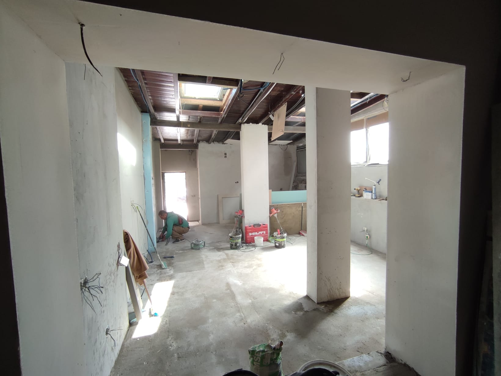 The Tasca during &mdash; open-plan room taking shape, structural walls plastered, skylight cut into the timber ceiling, a worker on the floor on final fixes