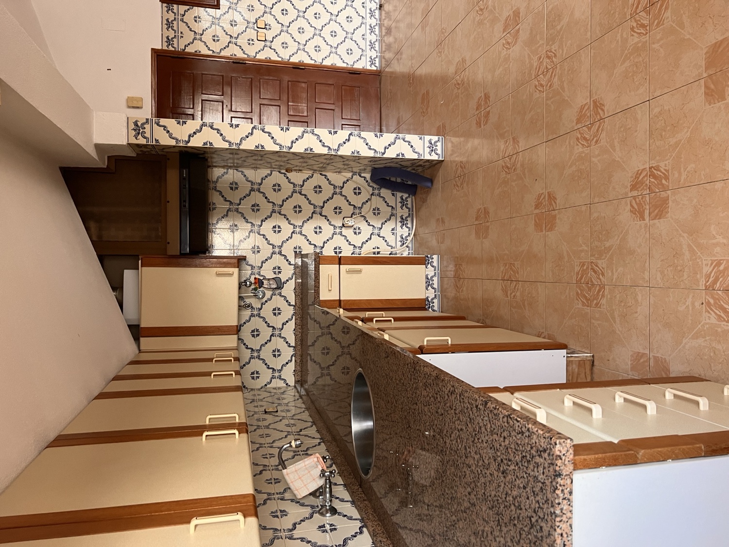 Vista before &mdash; original kitchen with blue azulejo on the back wall, brown wood upper cabinets, cream laminate base, pink tile on the side walls