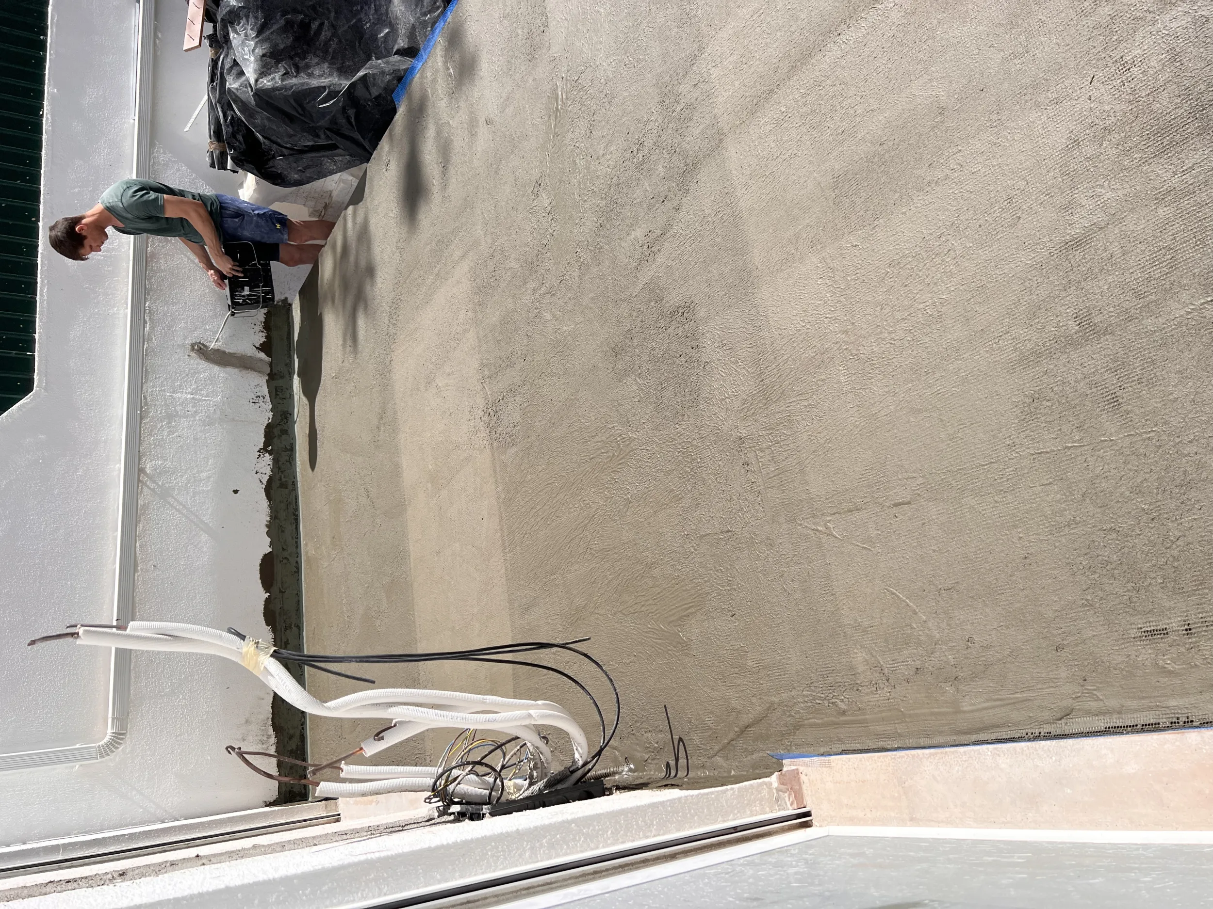 Rosa during &mdash; the rebuilt patio sub-floor in smooth cement screed, waterproofing membrane sealed against the perimeter walls, drainage conduits routed at the base