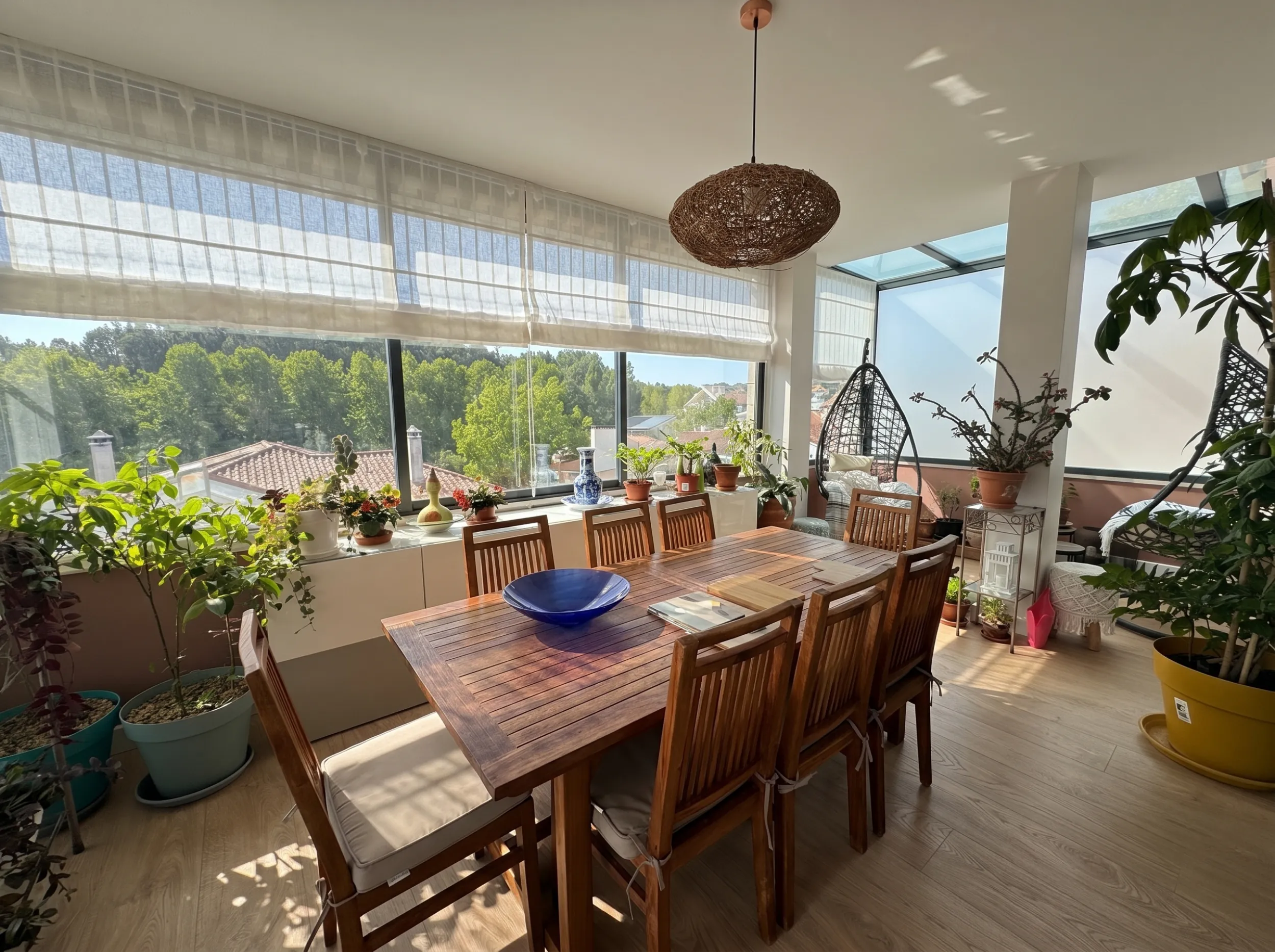 O atelier de varanda envidra&ccedil;ada da Maja em Alcabideche &mdash; mesa comprida onde se fazem os desenhos e as amostras, com vista para &aacute;rvores e telhados