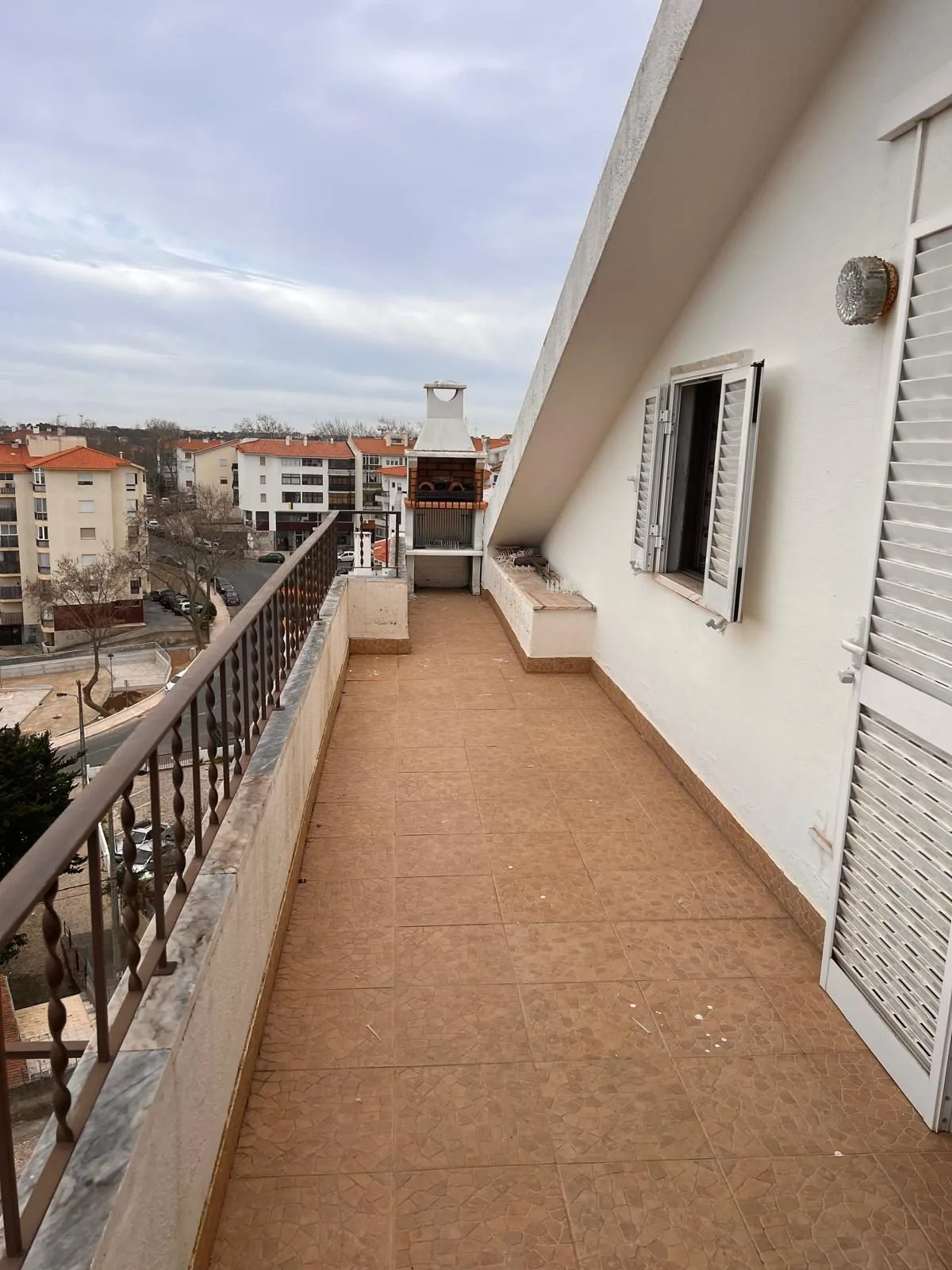 Vista before &mdash; original balcony with terra-cotta tile, plain black metal railing, view across white rooftops