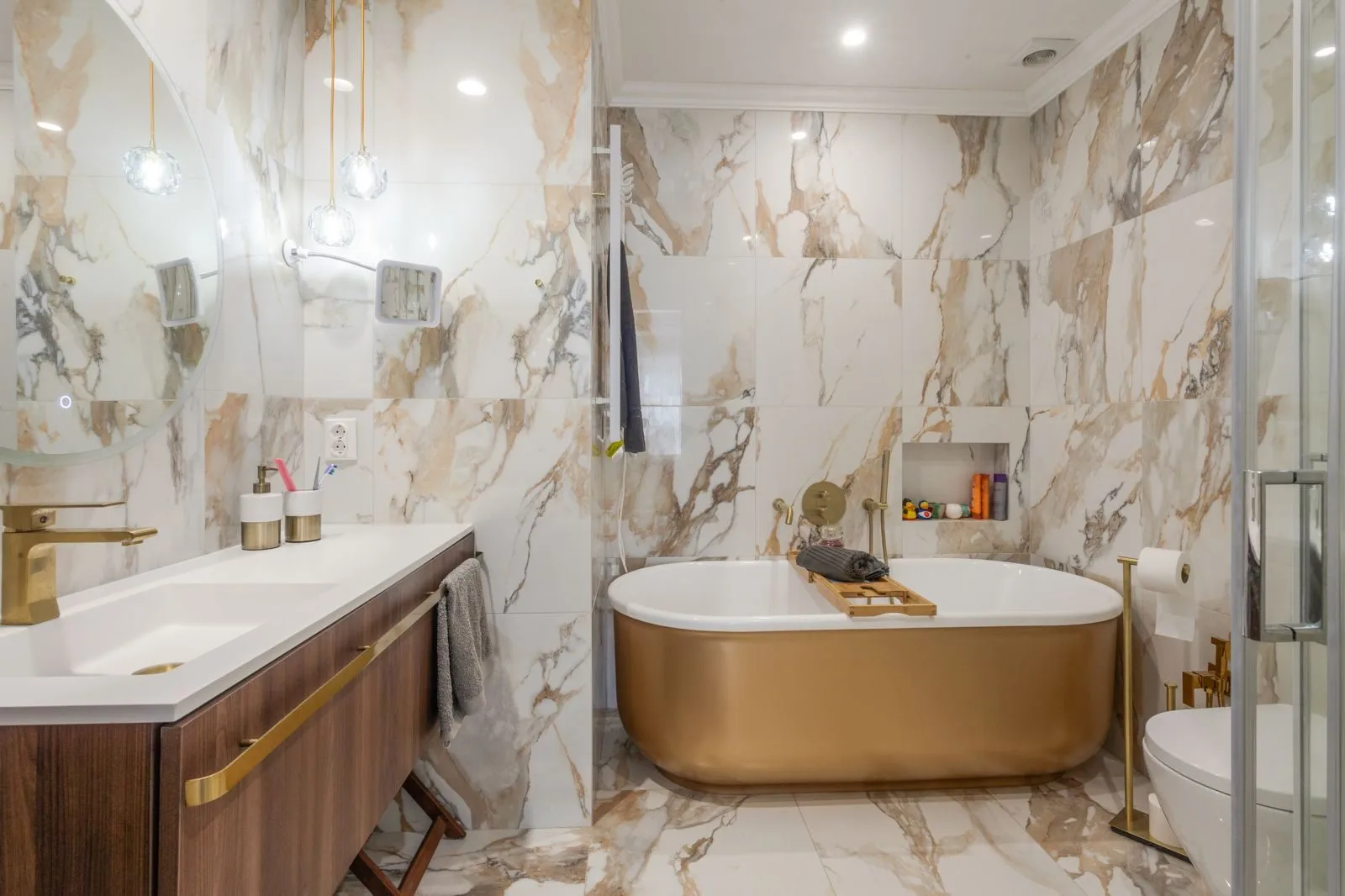 Gold bathtub and porcelain tile bathroom — Parede renovation by Maya's Homes