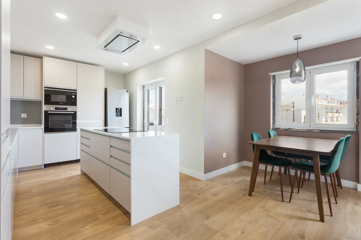Figueiras kitchen island and dining area with a mauve wall and green chairs