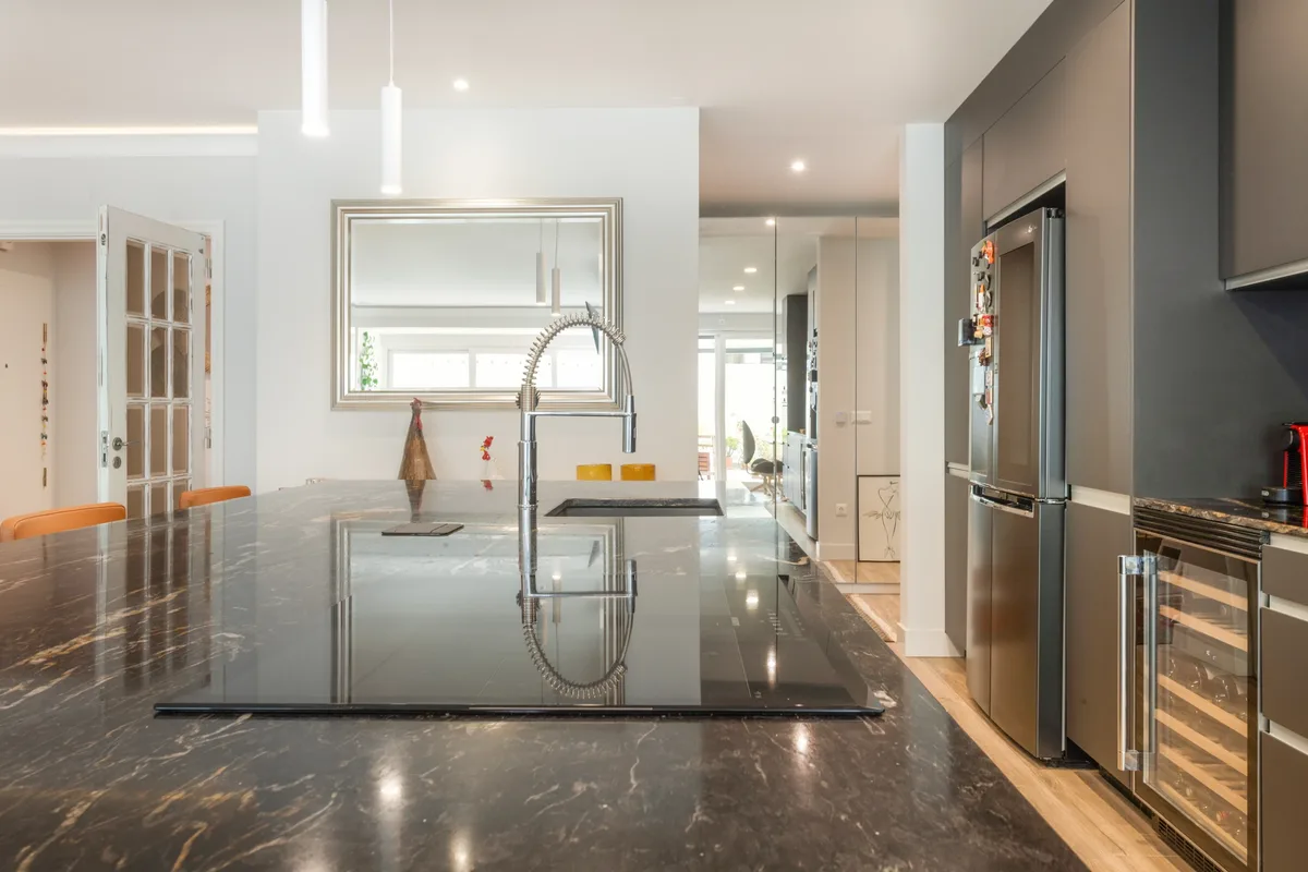 Rosa — Dark kitchen island with integrated hob and sink.