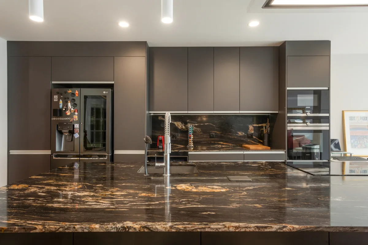 Rosa — Kitchen cabinetry and stone worktop viewed across the island.