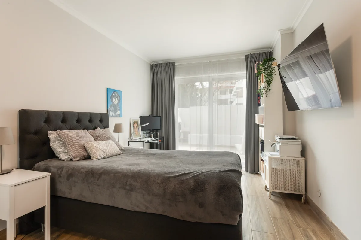 Rosa — Bedroom with a dark upholstered headboard and glazed doors.