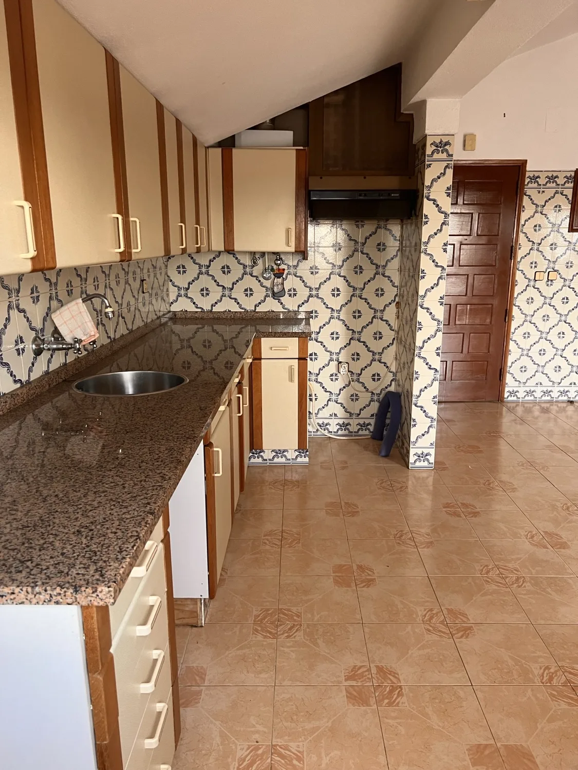 Vista before &mdash; original kitchen with blue azulejo on the back wall, brown wood upper cabinets, cream laminate base, pink tile on the side walls