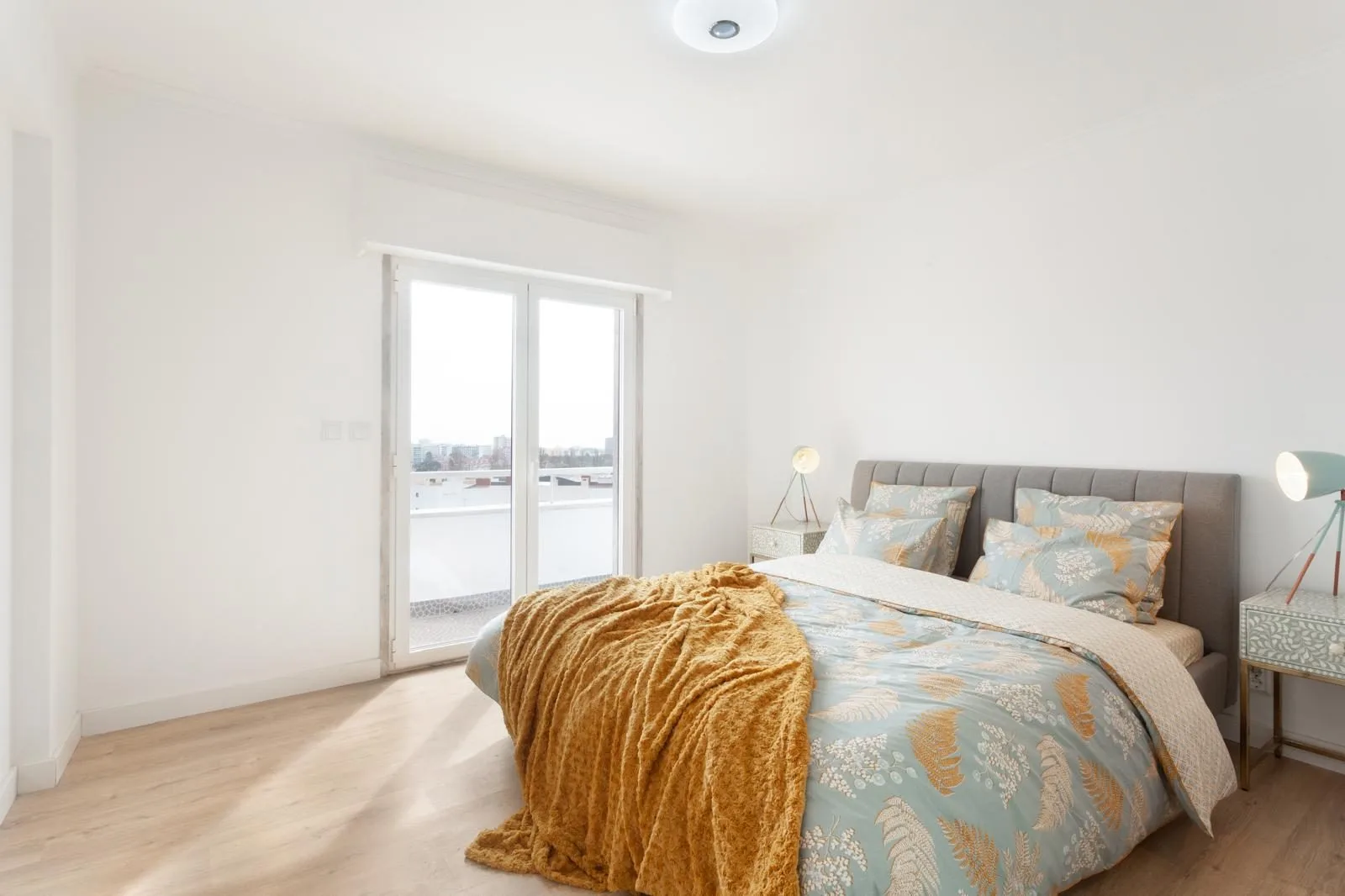 Master bedroom with city views and balcony access — Rebelva T2 renovation Cascais by Maya's Homes